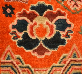 This Tibetan under-saddle carpet or ‘makden’ has a floral design on either side in a reddish-orange main field with abstract clouds and mountains at either end and is enclosed by a narrow,  ...