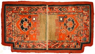 This Tibetan under-saddle carpet or ‘makden’ has a floral design on either side in a reddish-orange main field with abstract clouds and mountains at either end and is enclosed by a narrow,  ...