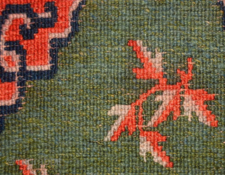 Tibetan khaden with a central mandala-like motif and leaves spread sparingly throughout a subtly abrashed marled-green main field. The main border is the interlocking T design highlighted with flowers at the cardinal  ...