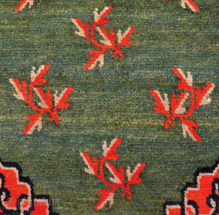 Tibetan khaden with a central mandala-like motif and leaves spread sparingly throughout a subtly abrashed marled-green main field. The main border is the interlocking T design highlighted with flowers at the cardinal  ...