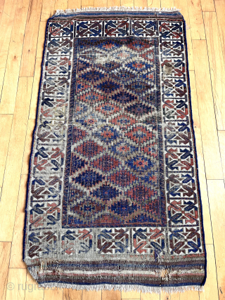 Antique Turkish knotted Baluch rug with an eye catching wide ivory border. Overall rough with low pile with heavy wear and substantial brown oxidation. Can’t quite put my finger on why but  ...