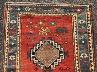 Antique small Kazak rug in good untouched condition with spacious drawing featuring charming large stylized humans. All natural colors including an attractive tomato red ground, sky blue border and an unusual lovely  ...