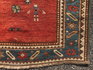 Antique small Kazak rug in good untouched condition with spacious drawing featuring charming large stylized humans. All natural colors including an attractive tomato red ground, sky blue border and an unusual lovely  ...