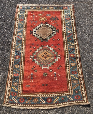 Antique small Kazak rug in good untouched condition with spacious drawing featuring charming large stylized humans. All natural colors including an attractive tomato red ground, sky blue border and an unusual lovely  ...