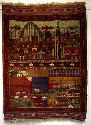 C107. A great example of a naive art “peace” period rug. 1990s. An imagined city that has everything - a big bridge, houses, office buildings aircraft, cars, boats, street lighting. 180x133cm. 5’11”x4’4”.  ...
