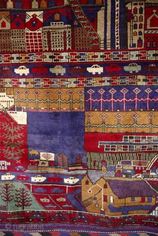 C107. A great example of a naive art “peace” period rug. 1990s. An imagined city that has everything - a big bridge, houses, office buildings aircraft, cars, boats, street lighting. 180x133cm. 5’11”x4’4”.  ...