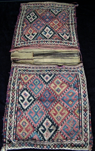 A complete rare early large Jaf style Kurdish zili heybe saddle bag. Unusual primitive abbreviated hands on hips type motifs, wool on wool flatweave foundation with a black goat hair warp. Hand  ...