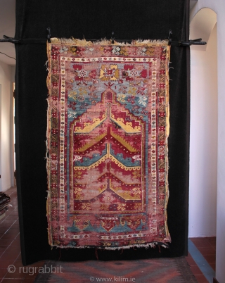  SOLD 19th century prayer rug from from Mucur in Kırşehir province, Central Anatolia.

An unusual mihrab with multiple arches, very good drawing and beautiful colours. Complete but worn with foundation showing, holes  ...