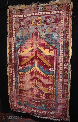  SOLD 19th century prayer rug from from Mucur in Kırşehir province, Central Anatolia.

An unusual mihrab with multiple arches, very good drawing and beautiful colours. Complete but worn with foundation showing, holes  ...