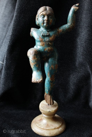 An 18th century carved wood temple figure of the Hindu god Krishna as a boy dancing. Carved, jointed and finished in gesso and blue polychrome. Mounted on an antique turned alabaster base  ...