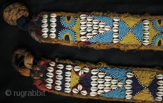 A pair of related but different antique tribal camel neck decorated bands. 

The bands incorporate a variety of materials and construction techniques. They are made using cowrie shells, hand made glass beads  ...