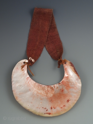 Kina Shell Pectoral,
Western Highlands, Papua New Guinea.
Pearl shell, natural fibers, cowrie shells, natural pigment.
9” high by 8.5” wide, strap is 19.5" long.
Early to mid-20th century.
Ex Robin Lail.      