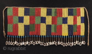 Pikuran (cache-sexe, Bana Guili people, Mandara Mountains, Cameroon. Seed beads, cotton string, cowrie shells. 16.25" (41.2 cm) wide by 8.25" (21 cm) high. With base 20.75" (52.7 cm) wide by 12.25" (31  ...