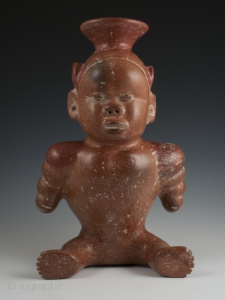 Seated dwarf vessel, Colima, West Mexico. Earthenware, slip, 11" (28 cm) high. 100 BC - 250 AD.

A reddish-brown painted earthenware seated dwarf with out-turned legs and bulging muscular arms. He wears a  ...