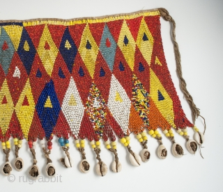 Pikuran (cache-sexe), Bana Guili people, Mandara Mountains, Cameroon. Seed beads, cotton string, cowrie shells, 19" (48.3 cm) wide by 9.5" (24 cm) high, mid 20th century or earlier.

The incredible variety of colored  ...