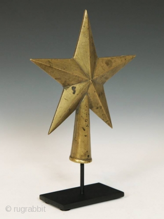 Star-shaped staff finial,
Africa.
Brass,
9" (22.8 cm) high by 6" (15.2 cm) wide by 2" (5 cm) deep, as based,
Mid 20th century             