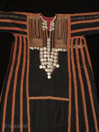 A traditional dress worn by women in the Western Desert of Egypt, this fustan is ornately decorated with thin silver coins, buttons and very fine cotton embroidery. There is a pocket on  ...