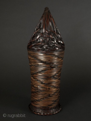 Japanese Antique Bamboo Basket

Japanese antique bamboo basket, tall narrow shape with circular handle. Design on body of zigzag alternating dark woven bamboo on lighter woven material. Ending in circular flattened foot. Interior  ...