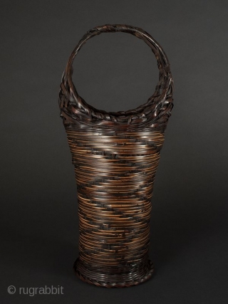 Japanese Antique Bamboo Basket

Japanese antique bamboo basket, tall narrow shape with circular handle. Design on body of zigzag alternating dark woven bamboo on lighter woven material. Ending in circular flattened foot. Interior  ...